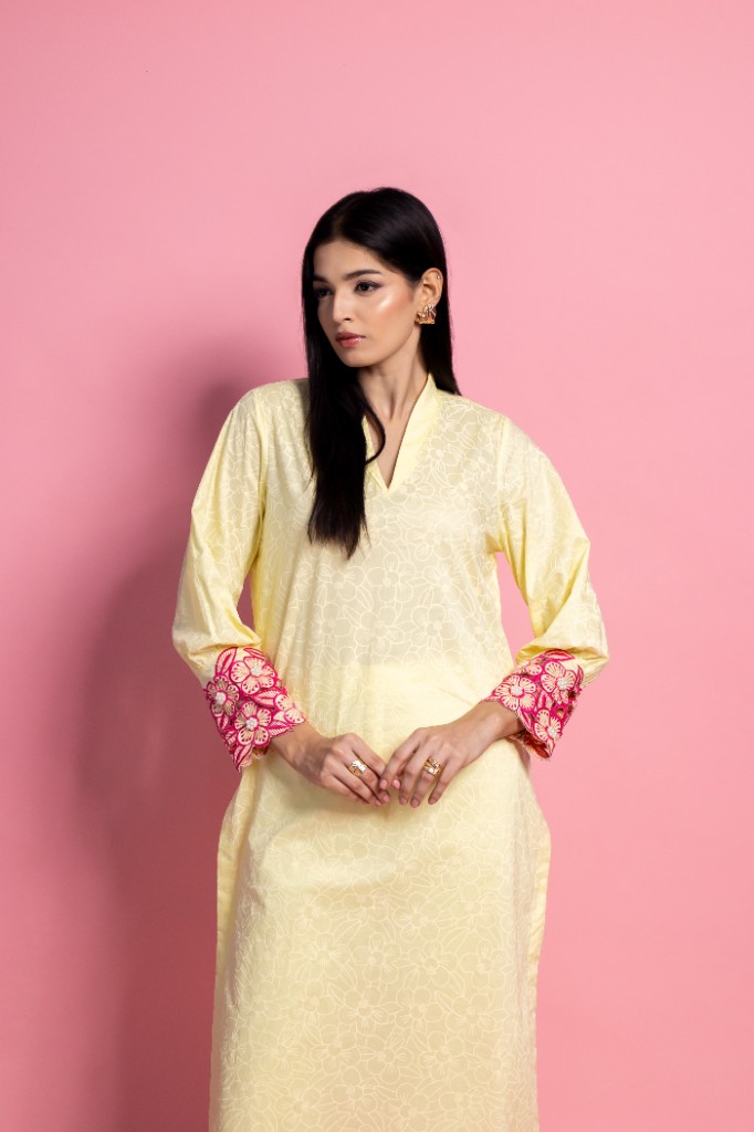 Festive Casuals — soft yellow tunic with pink embroidered cuffs on a pink studio backdrop.